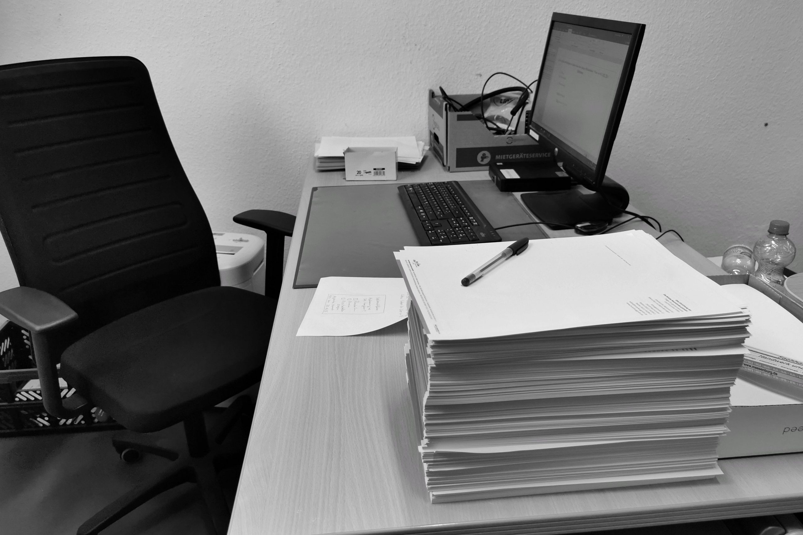Bureau désorganisé en noir et blanc avec paperasse et chaise