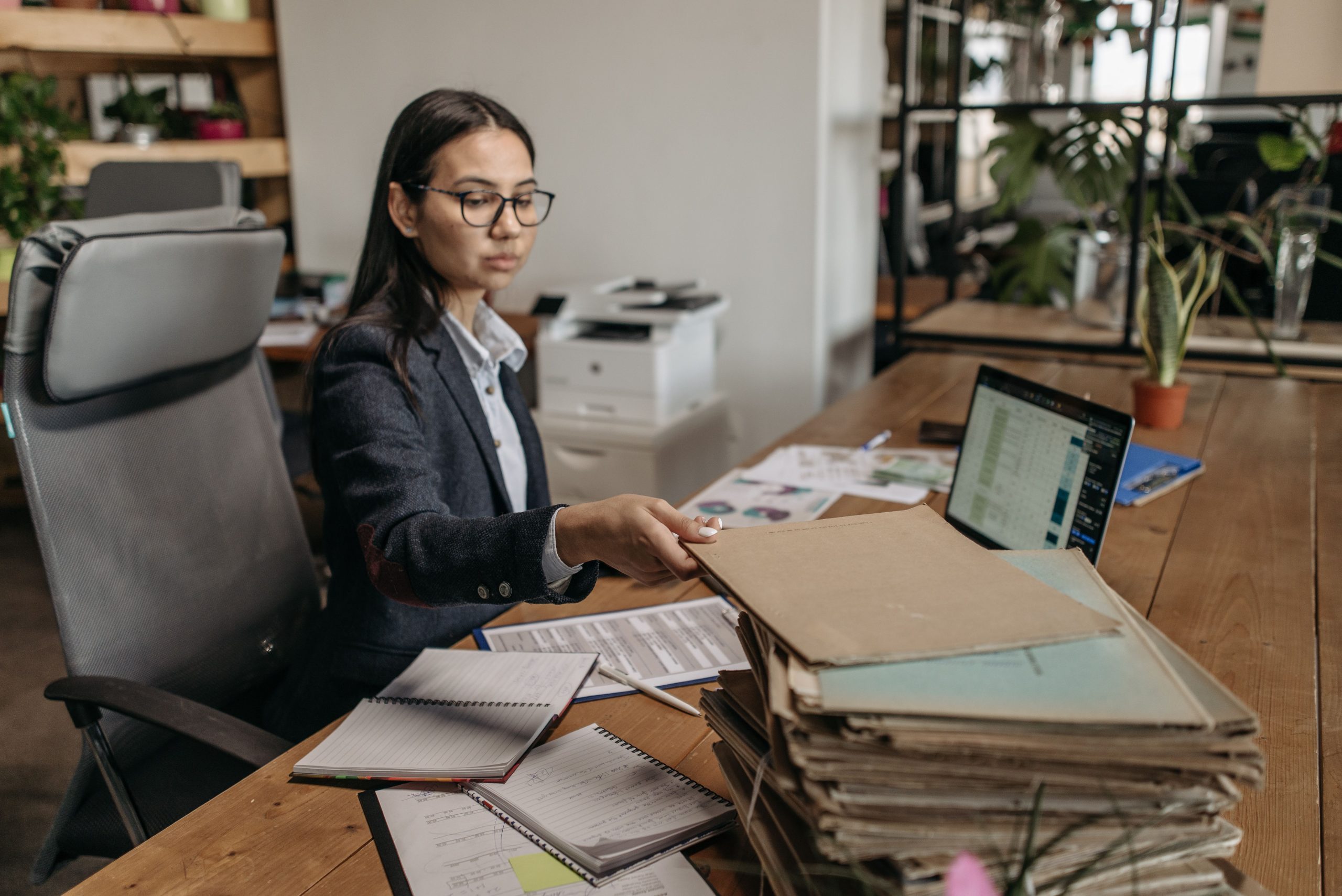 Femme travaillant à son bureau avec dossiers et ordinateur portable