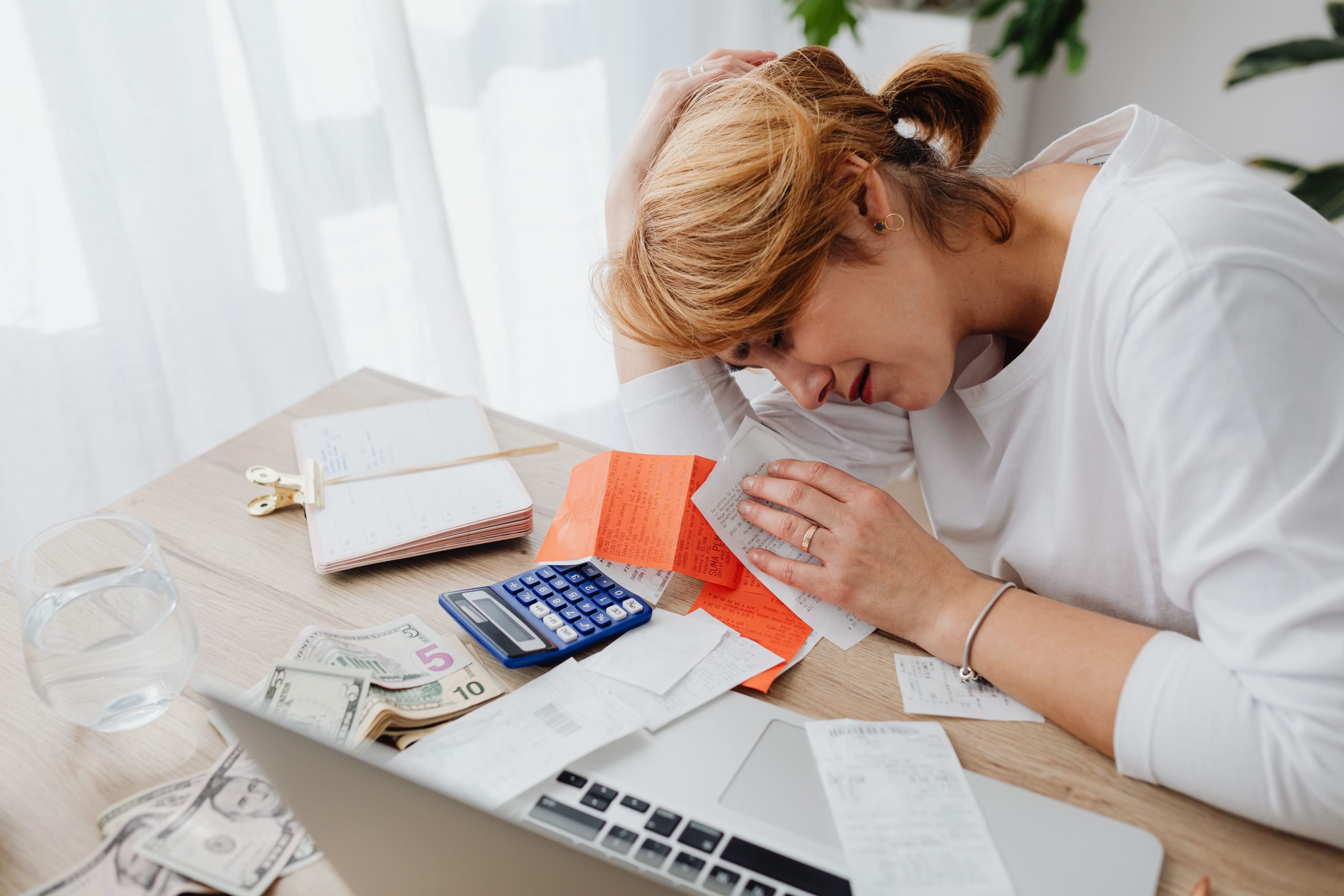 Femme stressée entourée de factures et calculatrice