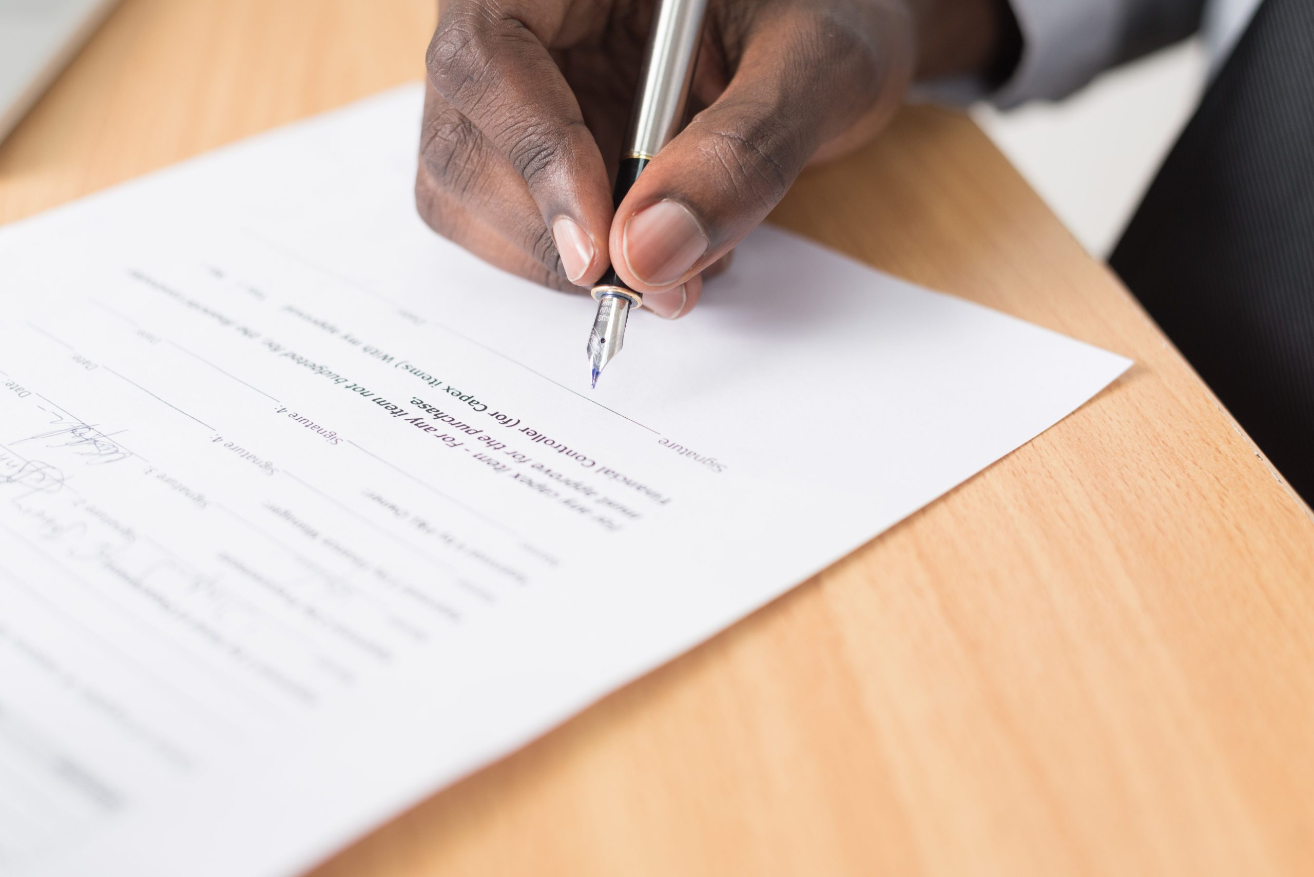 Main signant un document avec un stylo sur bureau