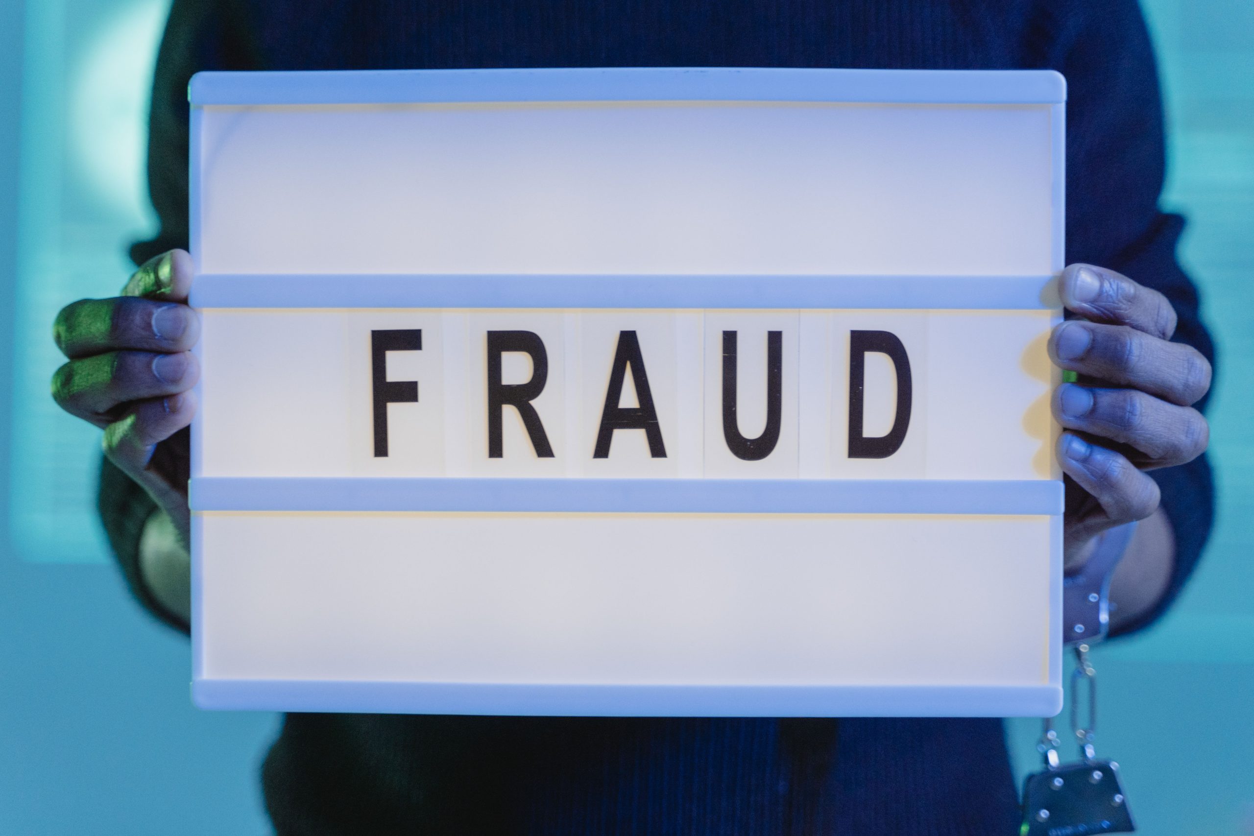 Mains tenant un panneau fraude eclaire en bleu