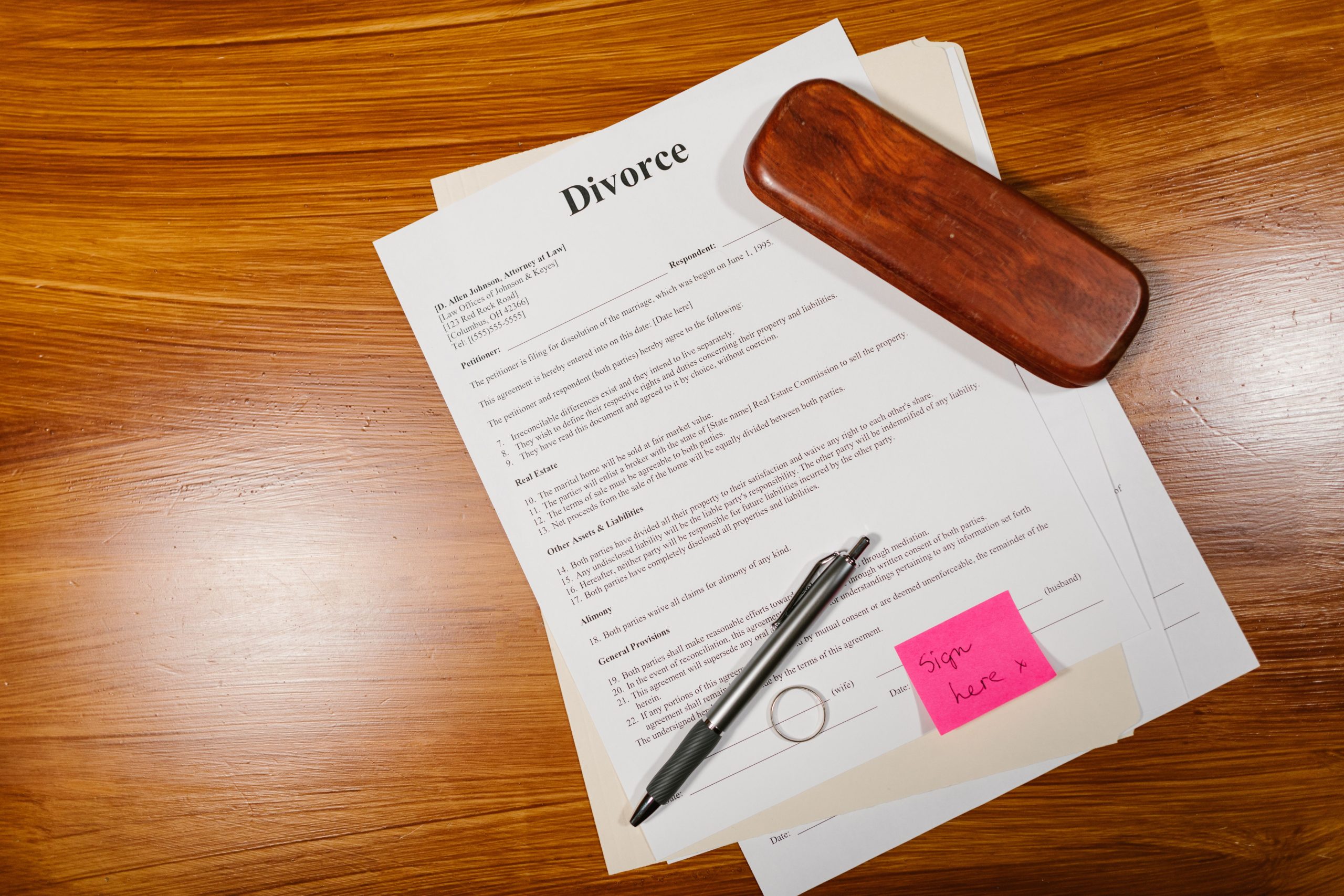 Documents de divorce avec stylo et alliance sur bois